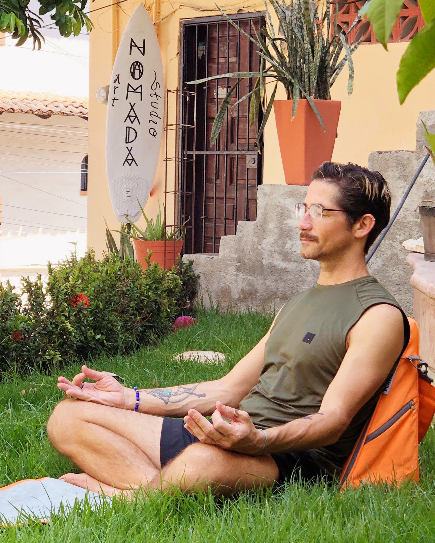A man using his Playamigo ground chair for a meditation session outside in the grass.