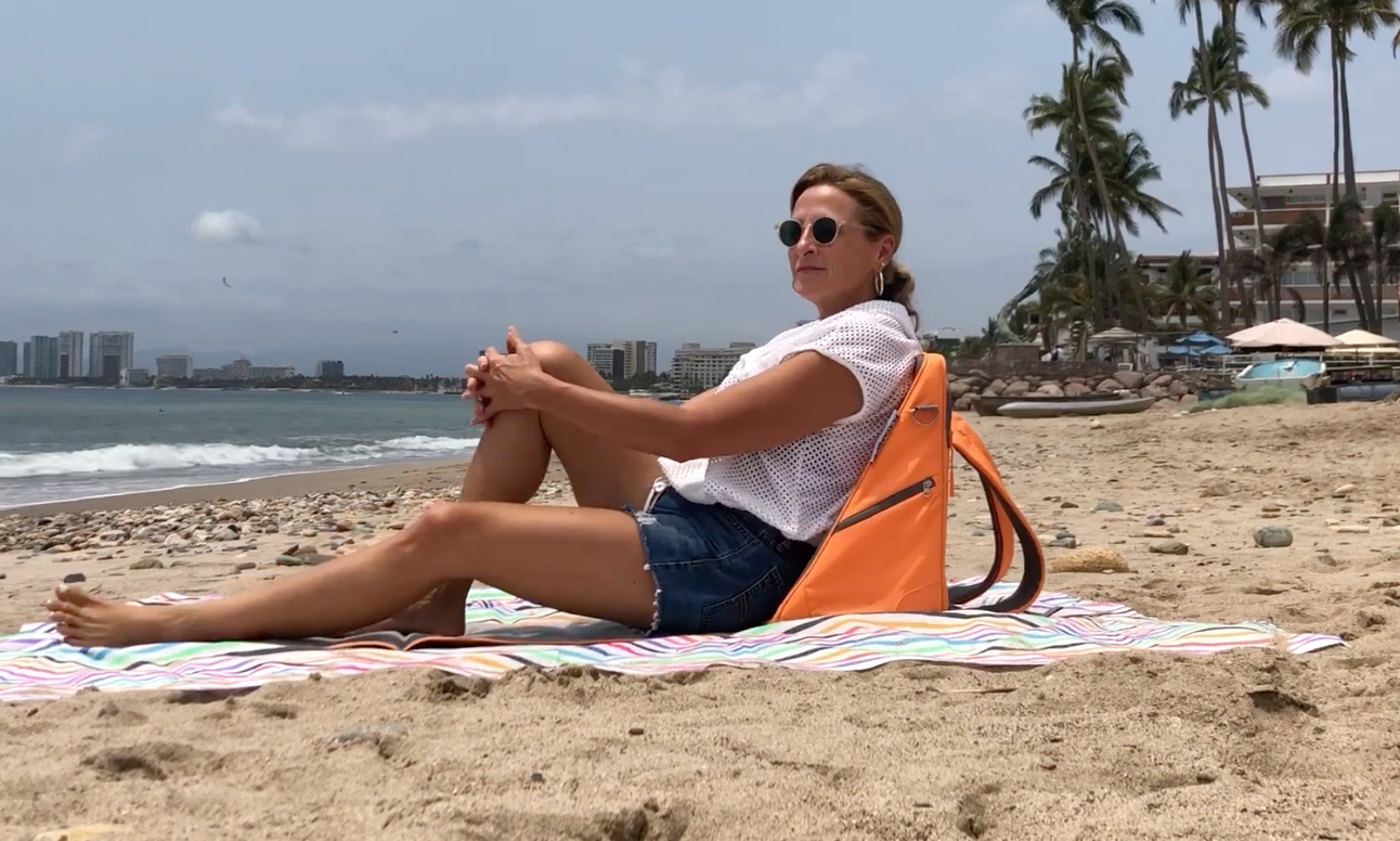 Load video: Video showing a woman setting up the Playamigo chair on the beach in the upright position.