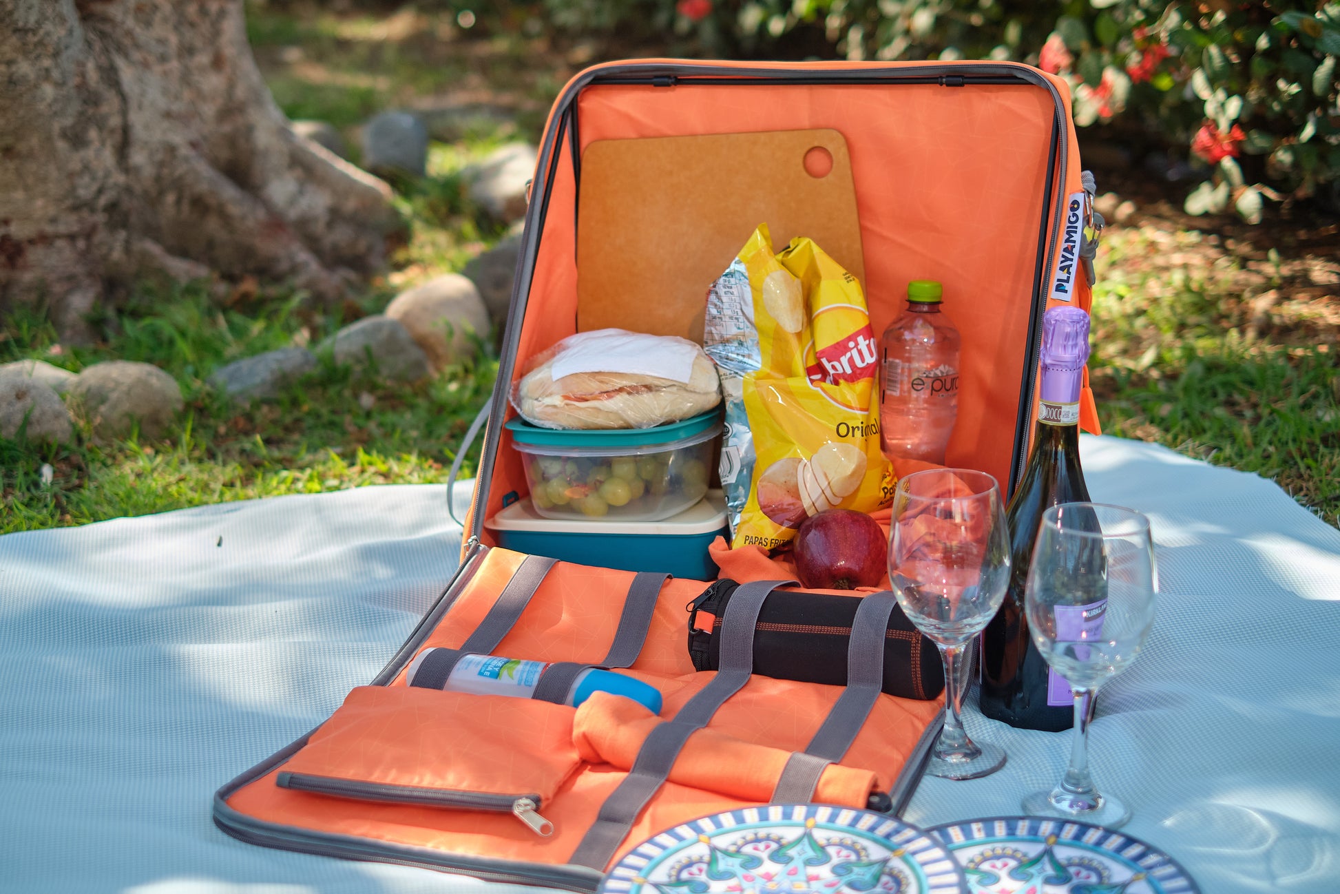 Interior carrying space of a Playamigo ground chair showing a variety of picnic supplies.